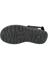 Black rubber sandal sole with textured tread pattern for grip, featuring indented lines and a circular button detail near the heel.