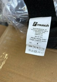 Black finger support brace with a textured fabric, featuring a white label detailing the product name, size, and care instructions.