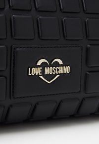 Black quilted faux leather handbag featuring a gold-tone "Love Moschino" logo with heart design and textured surface.