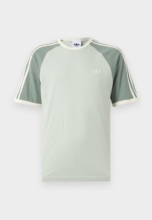 Svijetlozelena Adidas majica s tamnozelenim raglan rukavima, bijelim obrubom, tri bijele pruge na rukavima i Adidas logom u obliku lista djeteline na prsa.