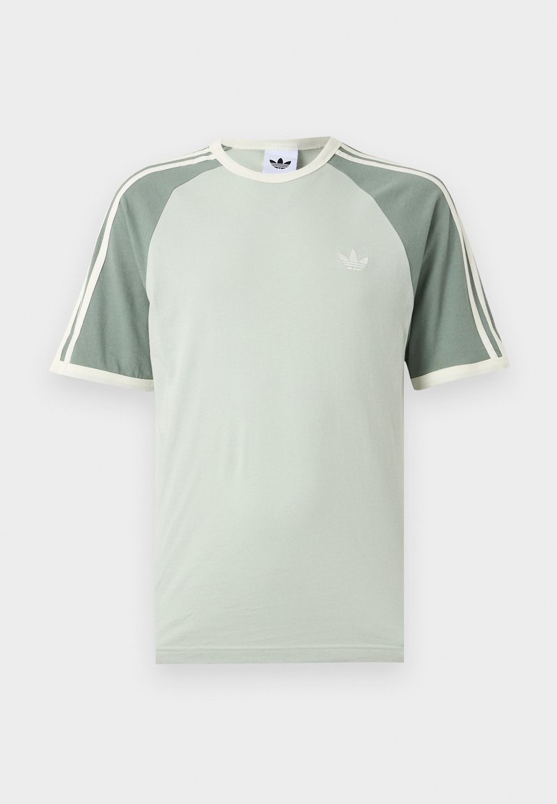 Lysegrøn Adidas T-shirt med mørkere grøn raglanærmer, hvid kant, tre hvide striber på ærmerne og Adidas trefoil-logo på brystet.
