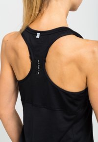 Černý atletický top bez rukávů s designem racerback, hladkou texturou a jemným švem na zadní straně s malými kovovými akcenty.