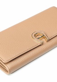 Cartera de cuero en beige claro, con un acabado texturizado, diseño plegable y un detalle de herrajes en tono dorado en forma de lazo.