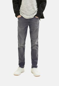 Jeans in denim grigio con vestibilità regular, dotati di cinque tasche e una leggera scoloritura. Abbinati a sneakers bianche per un look casual.