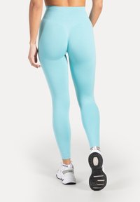 Leggings de tiro alto en azul claro, fabricados con un tejido elástico, que presentan un patrón de malla texturizada en los lados y un acabado liso.