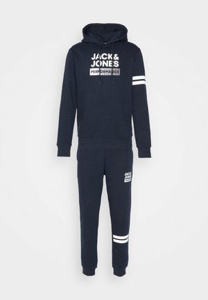 Ensemble de sweat à capuche et jogging bleu marine, en mélange de coton. Comprend un logo imprimé, une capuche avec cordon de serrage, des poignets côtelés et des accents de rayures blanches sur les manches et les jambes.