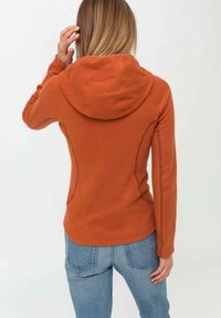 Orangene Fleece-Hoodie mit weicher Textur, tailliertem Design und rundem Kapuzenaufsatz. Sichtbare Nahtakzente und ein geschwungener Saum verbessern die Form.