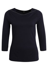Mörkblå långärmad topp med båtringning, med kontrastsömmar längs ringningen och en figurnära silhuett.