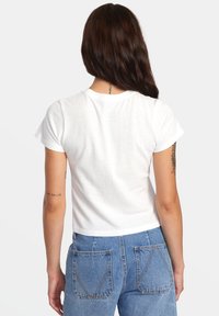 White short-sleeve cropped t-shirt made of soft cotton, featuring a round neckline and flat seams, paired with high-waisted blue denim jeans.
