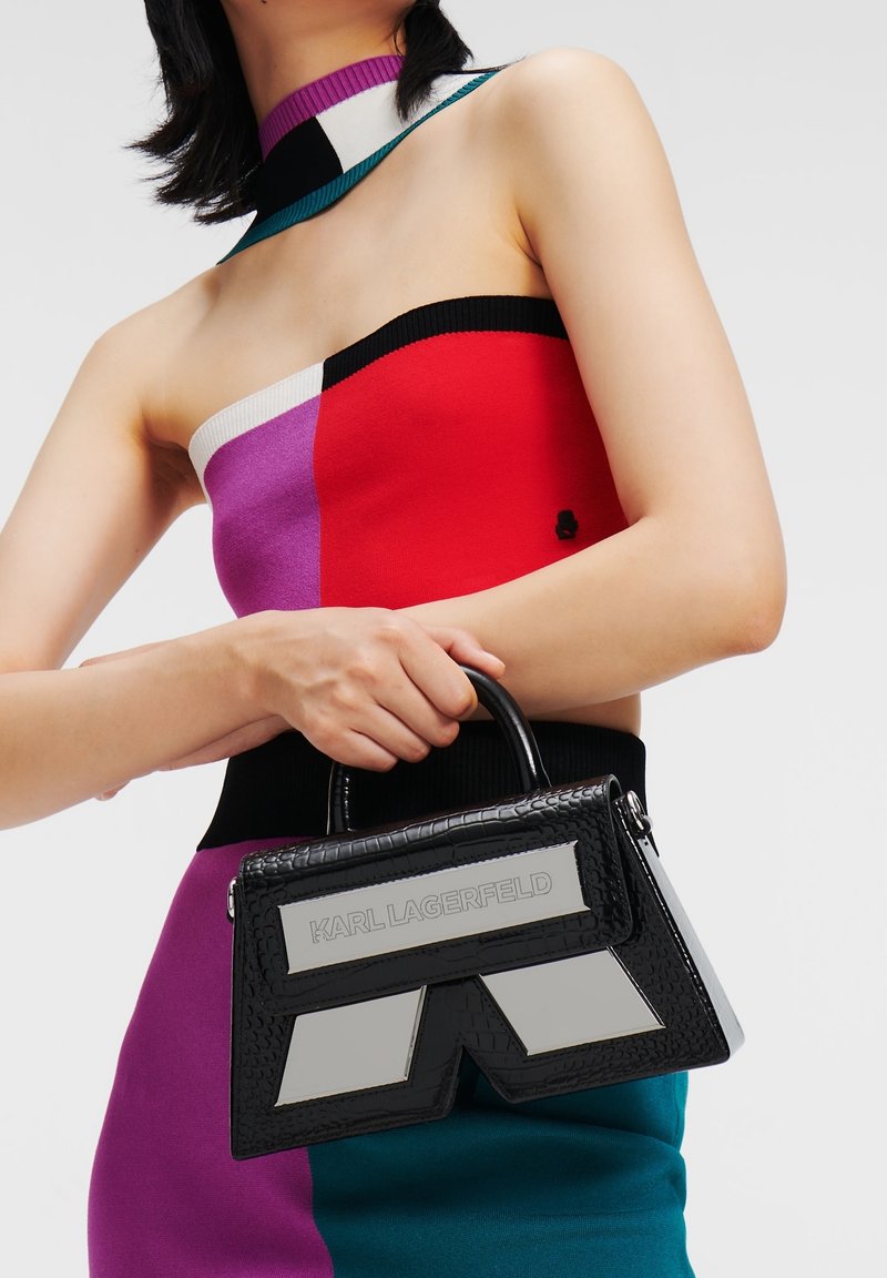 Svart handväska med krokodilmönster och en strukturerad form, med silverdetaljer och "KARL LAGERFELD" präglat på framsidan.