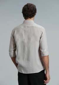 Lichtbeige linnen shirt met opgerolde mouwen, button-down kraag en een afgeronde zoom, met een zachte, gestructureerde stof aan de achterkant.