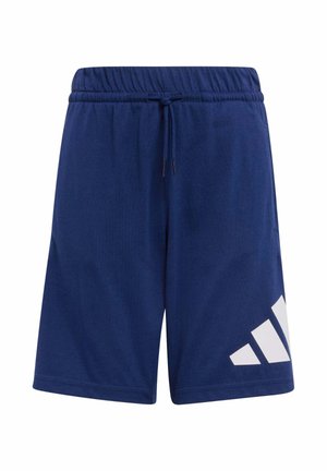 Dwie dziewczyny ubrane w pasujące jasnoróżowe bluzy z kapturem, niebieskie spodenki Adidas, białe skarpetki oraz białe trampki, stojące obok siebie na jednolitym tle.