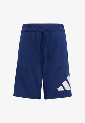 Deux filles portant des sweats à capuche rose clair assortis, des shorts Adidas bleus, des chaussettes blanches et des baskets blanches, debout côte à côte devant un fond uni.