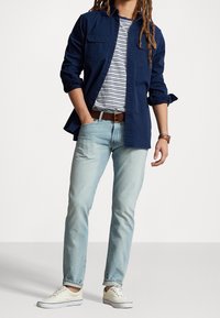 Laivastonsininen nappipaita valkoisen ja laivastonsinisen raidallisen T-paidan päällä, vaaleansiniset farkut, ruskea vyö ja valkoiset tennarit. Rentoa ja kerroksellista asustusta.