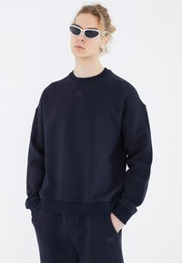 Marineblauer Sweatshirt aus weichem Material mit Rundhalsausschnitt und gerippten Bündchen. Mit einem dezenten Logo auf der Vorderseite und lässiger Passform.