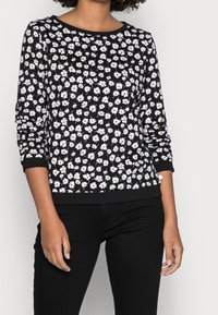 Maglione nero a maniche lunghe con un motivo floreale bianco. Presenta un collo a giro e polsini e orlo a coste. Tessuto morbido e leggero.