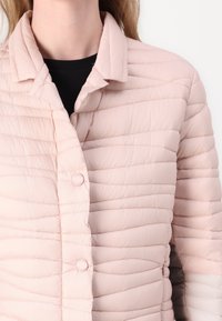 Ανοιχτό ροζ επενδυμένο μπουφάν με κολάρο, που διαθέτει οριζόντια ραμμένα σχέδια και κυκλικά κουμπιά κατά μήκος του μπροστινού μέρους.