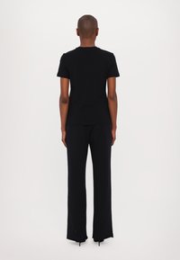 Juoda trumpa rankovė T-marškiniai ir plačios kelnės. Minkšta medžiaga, laisvas siluetas ir nusitrynęs apvadas. Paprastas, monochrominis dizainas.