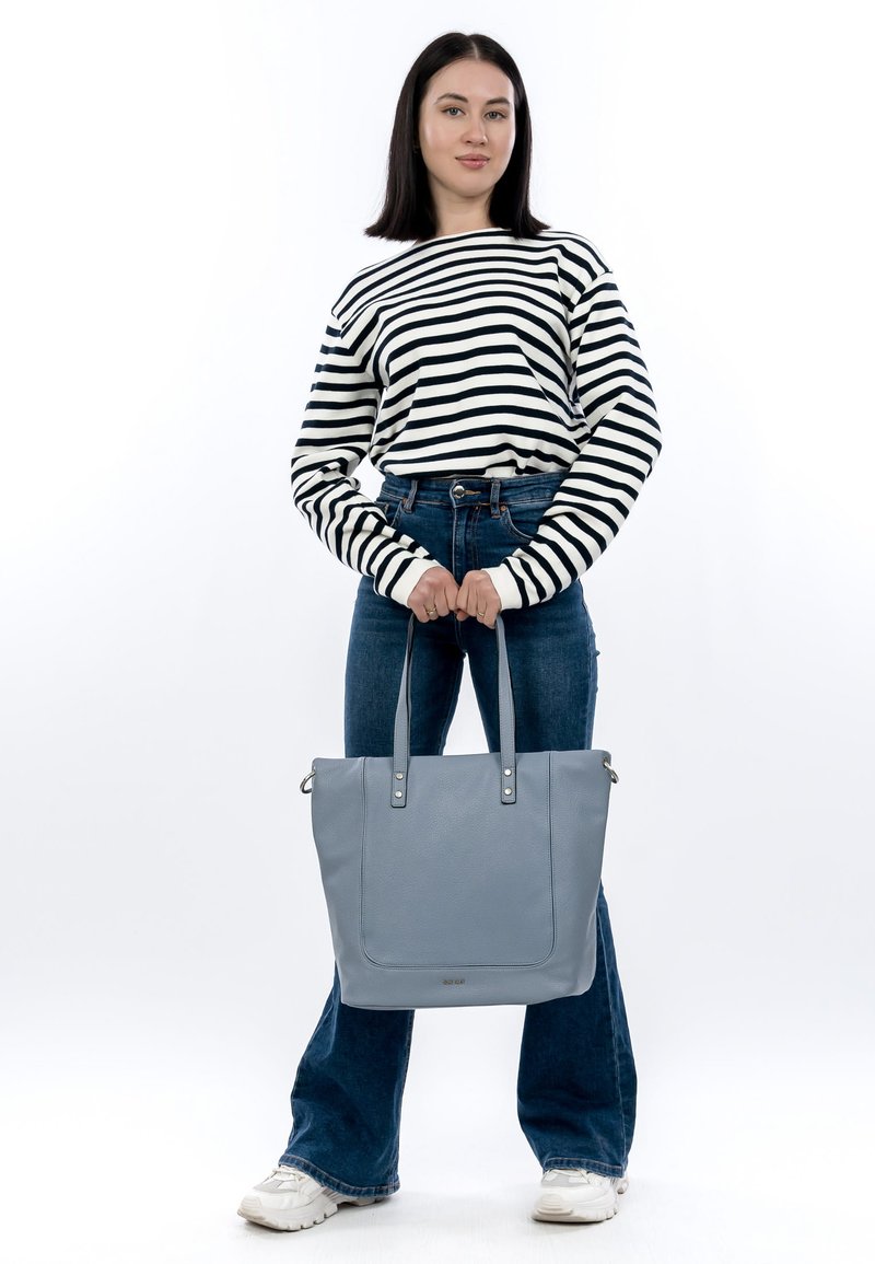 Sac fourre-tout en cuir bleu clair avec deux poignées, de forme rectangulaire, surface texturée et détails en métal argenté.