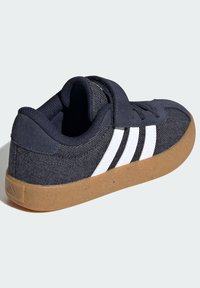 Tmavě námořnické tenisky s bílými pruhy, textilní svrchní část, gumová podrážka a suchý zip. Obsahují texturovanou látku a polstrovaný límec.