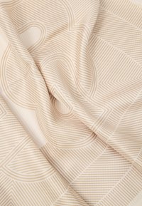 Tecido padronizado com um fundo creme e linhas e formas geométricas em bege. Textura suave com um design moderno e minimalista.