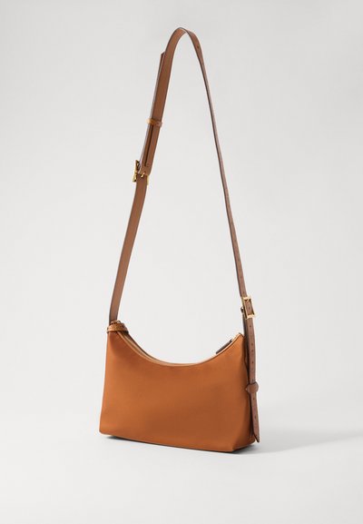 Brun smal rektangulär crossbody-väska med en justerbar läderrem och ett guldfärgat dragkedjestängning, uppvisad mot en enkel bakgrund.