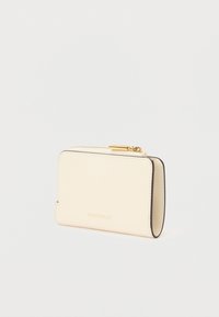 Cartera de cuero beige compacta con cremallera dorada y el logotipo de COCCINELLE grabado en la parte frontal, mostrada sobre un fondo blanco.