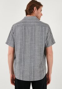 Korte mouwen overhemd met knopen in zwart-witte verticale strepen, met een ontspannen kraag en textuurstof met een rugpand detail.