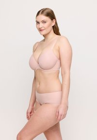 Jasnoróżowy komplet bielizny składający się z gładkiego, wyprofilowanego biustonosza z regulowanymi ramiączkami oraz bezszwowych majtek typu hipster. Oba elementy wykonane są z miękkiego materiału.