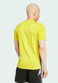Geel sportshirt met korte mouwen, gemaakt van een gestructureerde stof en blauwe zijaccenten. Het shirt heeft een ronde halslijn en een relaxte pasvorm.