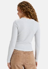 Long-sleeve top in soft, lightweight fabric, featuring horizontal blue and white stripes, round neck, and a fitted silhouette.