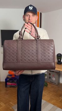 Bruine leren reistas met geperst patroon, dubbele handgrepen en een vlakke bodem. Soepele textuur en stevig ontwerp.