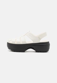 White plastic sandal with cut-out straps and a black platform sole. Features a back strap for support and textured side accents.