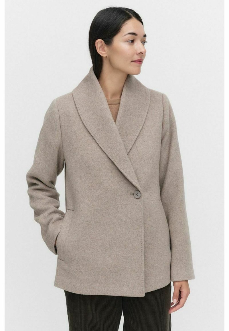Beige wool blend coat with a shawl collar, single button closure, side pockets, and a straight fit design. Smooth texture.