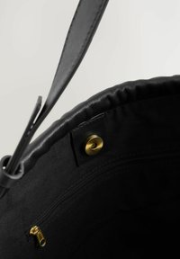 Musthave mustkott musta nahast väliskattega, ümar ülemine osa, kuldne metallist tõmblukk ja klõps sulgur. Sisemus on voodrita.