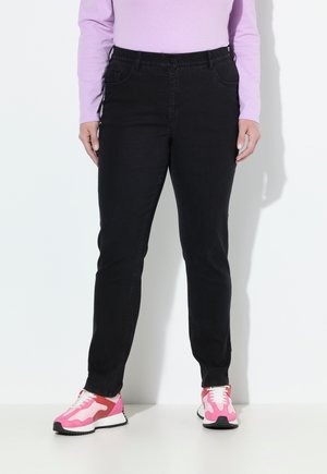Jeans neri con vestibilità slim e vita elastica, completati da tasche frontali. Abbinati a sneakers sportive vivaci rosa e bianche.