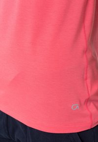 Coral-colored short-sleeve t-shirt made of soft fabric, featuring a subtle logo at the hem and a smooth texture with a fitted design.