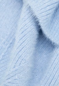 Tela de punto azul claro con una textura suave y esponjosa. Presenta patrones acanalados y fibras finas, creando una apariencia acogedora.