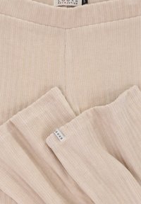 Beige ribbelstof met een zachte textuur; inclusief een merklabel met "LOOXS" en een horizontale naaddetail.