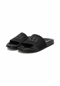 Chanclas negras de plástico mate, presentan un gran logotipo "Xti" en relieve, plantilla moldeada y suela plana para comodidad y estilo.