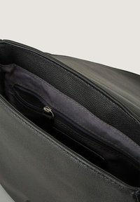 Interno di una borsa nera in finta pelle che mostra un rivestimento in tessuto scuro con una tasca con cerniera, mettendo in evidenza una texture liscia e compartimenti ben organizzati.