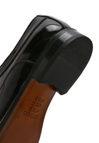 Zwarte gepatineerde leren schoen met een ronde neus en een lage blokhakken. Het interieur heeft een bruine leren voering met geperste logodetails.