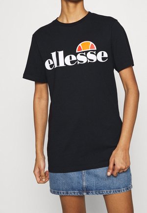 Czarna bawełniana koszulka z białym logo "ellesse" i półokrągłym wzorem w kolorze pomarańczowym i żółtym, zestawiona z dżinsową spódnicą. Krótkie rękawy.