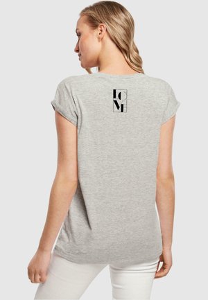 T-shirt grigio a maniche corte con risvolti, caratterizzato da un logo grafico nero sul retro. Realizzato in un tessuto morbido e liscio.