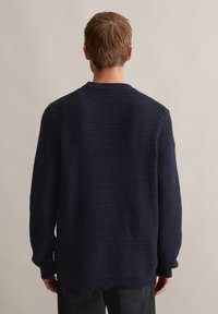 Dunkelblauer strukturierter Pullover mit Rundhalsausschnitt und langen Ärmeln, der ein Waffelmuster sowie gerippte Bündchen und Saum aufweist.