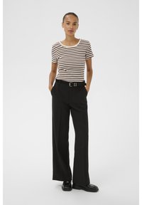 Striped short-sleeve t-shirt in cream and brown, paired with black high-waisted trousers featuring a wide leg and a belt with a silver buckle.