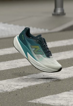 Hardloopschoen met een blauwegroene en witte verloopkleur, zwarte veters en neon groene "N" logo, vastgelegd in de lucht boven een zebra op asfalt.