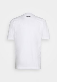 Bílá tílko s krátkým rukávem vyrobené z bavlny, s kulatým výstřihem. Malé černé logo adidas se nachází na horní části zad.