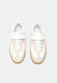 White and beige sneakers with pink accents, featuring a smooth leather upper, adjustable Velcro strap, and textured rubber sole.
