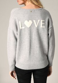 Pull léger gris avec "LOVE" et un cœur en crème, ourlet et poignets côtelés, texture douce et détail de bouton à l'arrière.